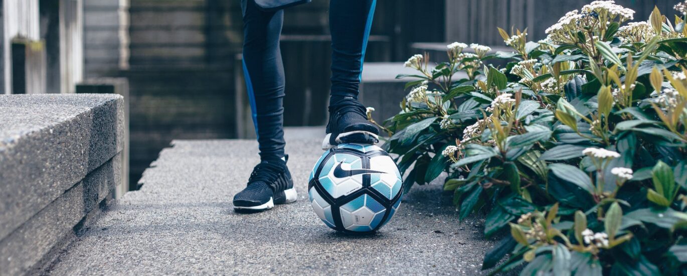 person in black leggings stepping on nike soccer ball